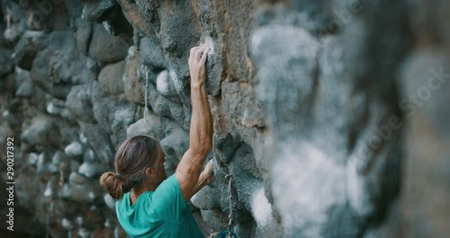 Strong rock climber lead climbing, moving quickly and skillfully, finding hand holds