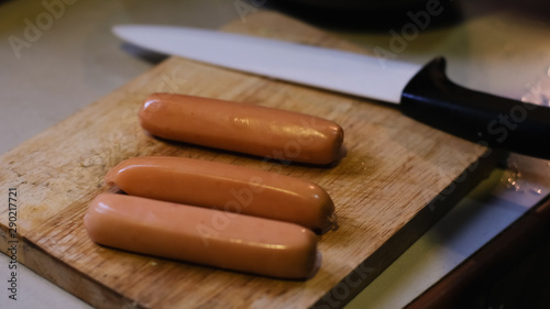 Selective focus of Fresh boiled sausages on wooden cutting board and knife background. preparing food.