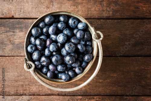 Delicious blueberries in rustic bowl on wooden table. Top view