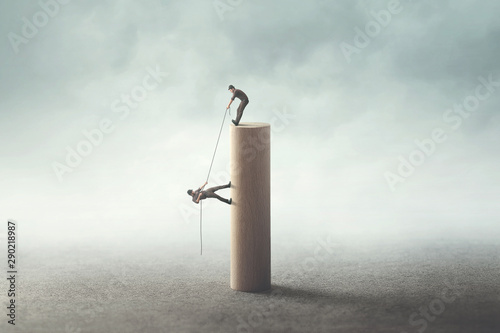 Photography business men helping each other to reach the top with a rope