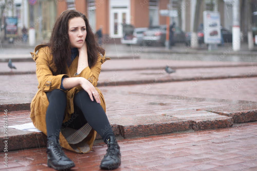 Sad young woman sitting outdoors in autumn on a rainy day. Sad young woman sitting outdoors in autumn on a rainy day.