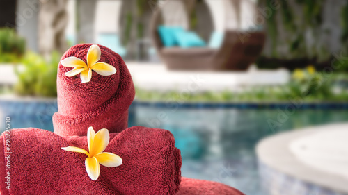 Towel and flowers on outdoor chair at resort spa with pool and garden in the background