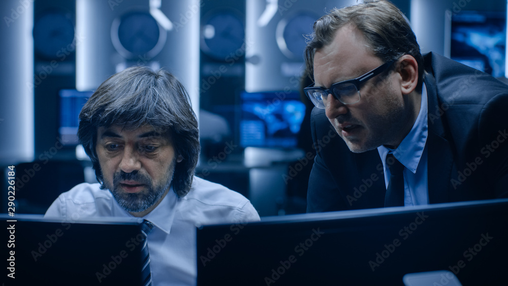 IT Professional Information Officer working on Personal Computer in System Control Room. They Have Work Optimization Discussion and Agree on Strategy. IT Professional Information Officer working on Personal Computer in System Control Room. They Have Work Optimization Discussion and Agree on Strategy.
