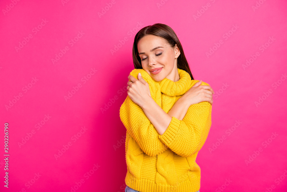 Portrait of cute girl embracing herself with closed eyes wearing yellow knitted sweater isolated over fuchsia background Portrait of cute girl embracing herself with closed eyes wearing yellow knitted sweater isolated over fuchsia background