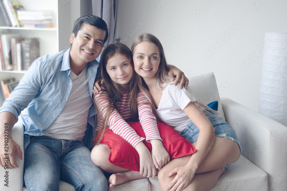 father and mother with daughter smiling and sitting on sofa together at home, happy young family concept. father and mother with daughter smiling and sitting on sofa together at home, happy young family concept.