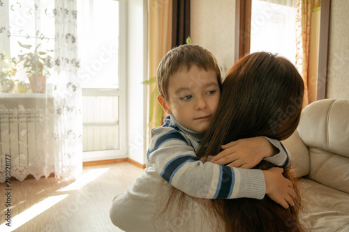 Valokuvatapetti Mom hugs her son at home with light from the windows