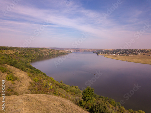 Top view of Dnestr  Dniester  river in autumn. River surrounds yellow field and green forest. Moldova republic of.