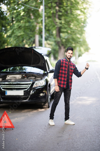 Handsome young indian man calling for assistance with his car broken down by the roadside. Try to stop car. © F8  \ Suport Ukraine
