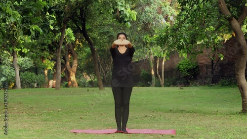 A young girl practicing tadasana / mountain yoga pose outside in a park.  photo