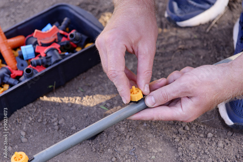 Prepared for planting in early Spring. faucet with red handle for drip irrigation. Drip Irrigation System Close Up. hose for drip irrigation in a skein. DIY drip irrigation system assembly