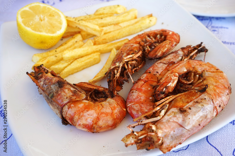 cooked dish of tiger prawns with fries on a plate in a seafood restaurant, close-up