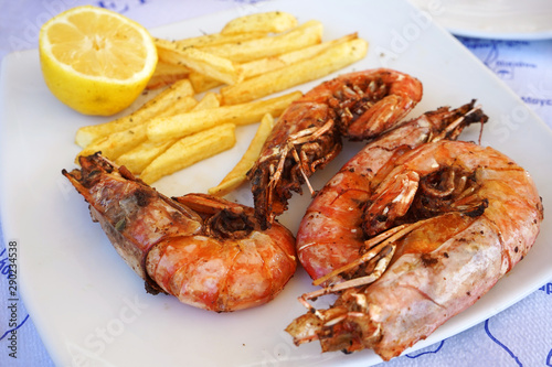 cooked dish of tiger prawns with fries on a plate in a seafood restaurant, close-up