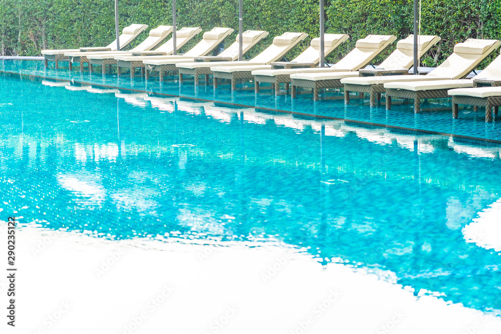 Umbrella and chair sofa around outdoor swimming pool in hotel resort for holiday vacation