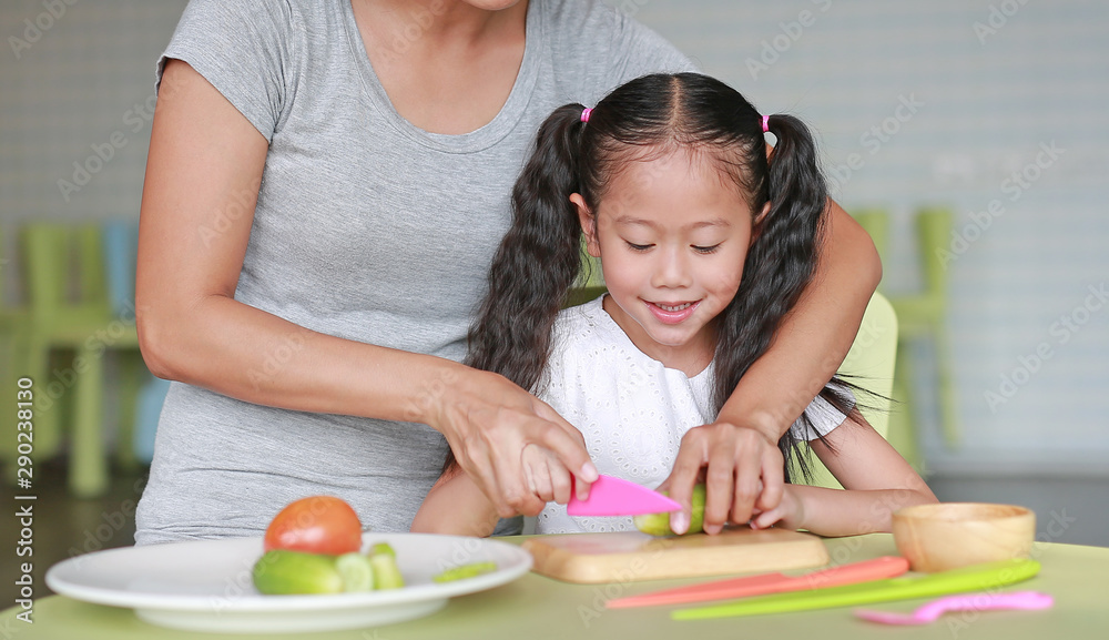 Close up Asian mom and daughter slicing vegetable on chopping board at play room. Mother teaches her little child girl to cooking. Close up Asian mom and daughter slicing vegetable on chopping board at play room. Mother teaches her little child girl to cooking.