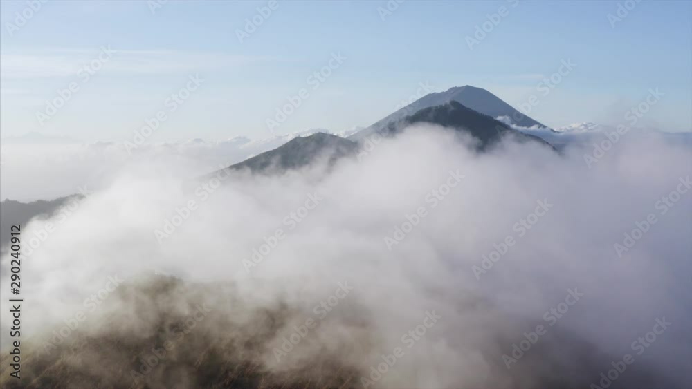 Aerial view of mysterious fog flying above volcanos in the morning.Sunrise. Bali island, Indonesia Aerial view of mysterious fog flying above volcanos in the morning.Sunrise. Bali island, Indonesia