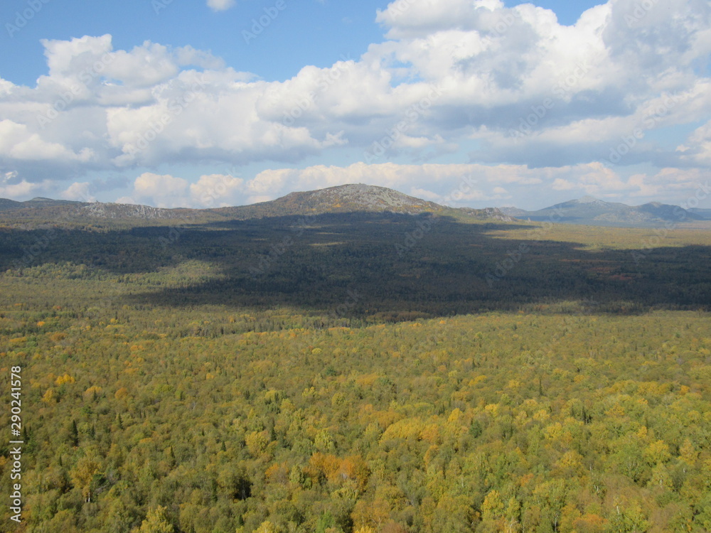 Ural mountains under cloudy Sunny sky in warm autumn.