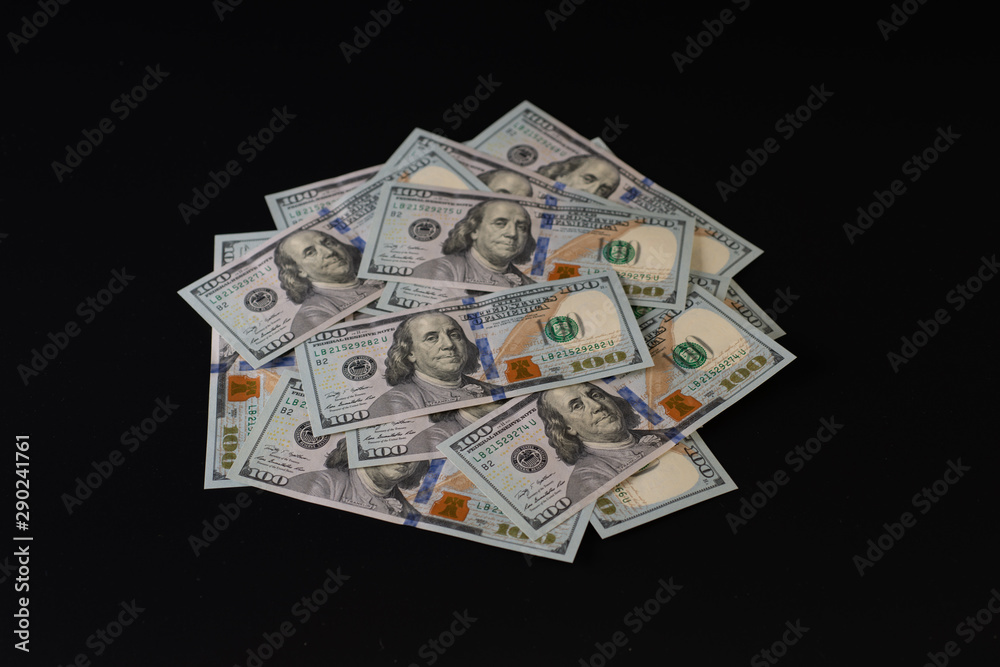 A pile of one hundred dollar bills on a black background