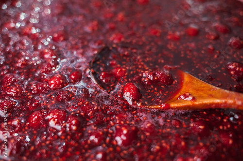 a wooden spoon is immersed in raspberry jam