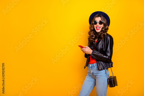 Portrait of shocked funny funky lady with curl hairstyle use her mobile phone read feednes in blogs scream wow omg wear black outfit denim jeans isolated over yellow color background