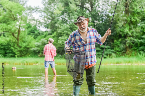 Fisherman with fishing rod. Activity and hobby. Fishing freshwater lake pond river. Bearded men catching fish. Mature man with friend fishing. Summer vacation. Happy cheerful people. Master baiter