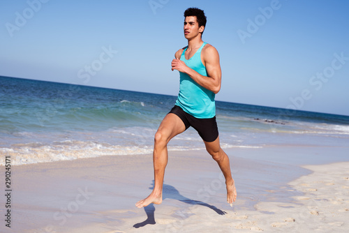 Young man sprinting on the beach in the sun