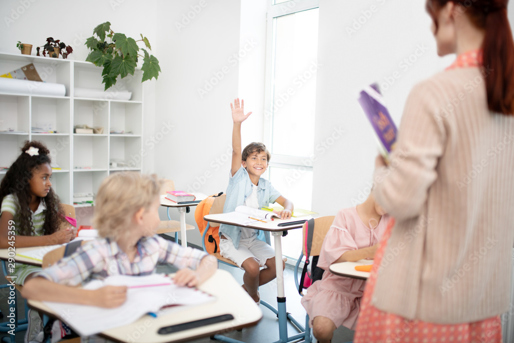 Fototapeta premium Dark-haired boy being very active during the English lesson