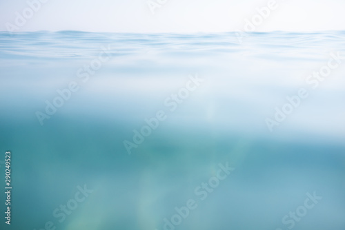 Blue calm sea with waves and rays of sunlight shining through, on the water surface and underwater. Ocean. Tranquility and silence. Beautiful natural background, wallpaper