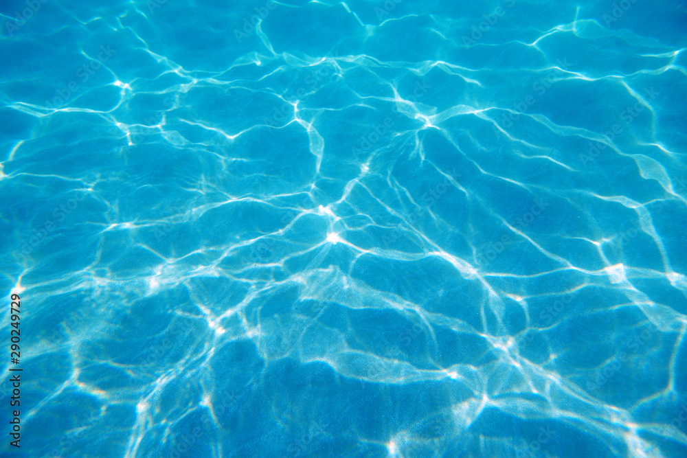 Underwater. Sun glare at the bottom of the seat. Waves underwater and rays of sunlight shining through. Deep turquoise blue sea. Ocean. Transparent water and light at sand.