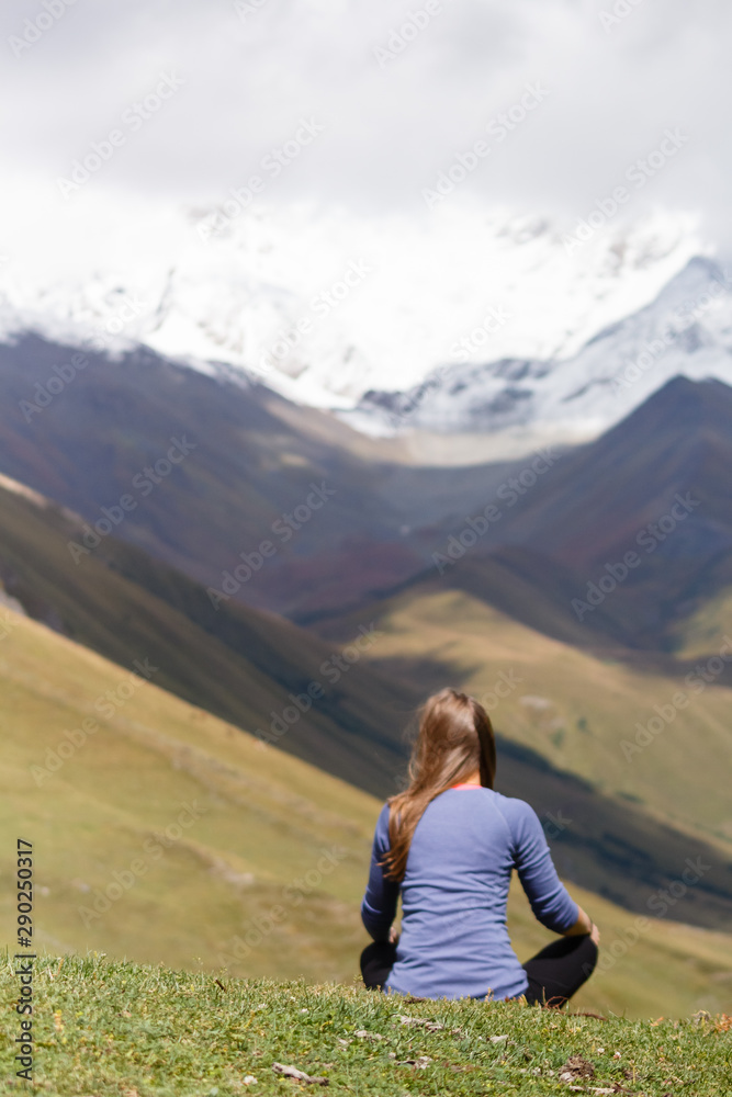 Young woman sitting in front of mountains, relaxing, travel and tourist concept
