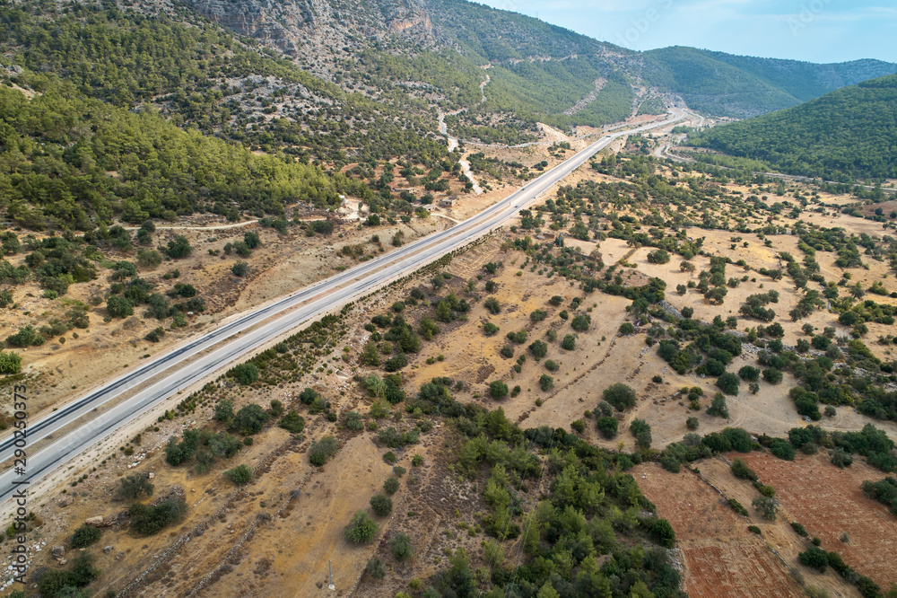 Asphalt road in the valley. Countryside highland landscape with agricultural fields and woods, aerial view Asphalt road in the valley. Countryside highland landscape with agricultural fields and woods, aerial view