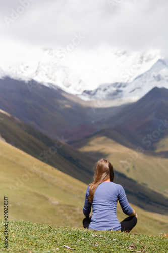 Young woman sitting in front of mountains, relaxing, travel and tourist concept