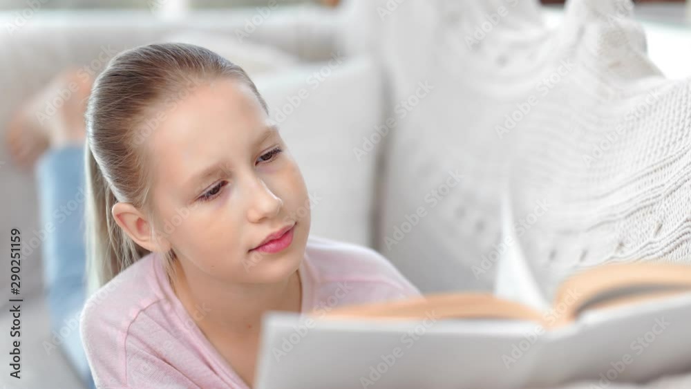 Close-up face cute child girl focused reading interesting book enjoying weekend at comfortable couch Close-up face cute child girl focused reading interesting book enjoying weekend at comfortable couch