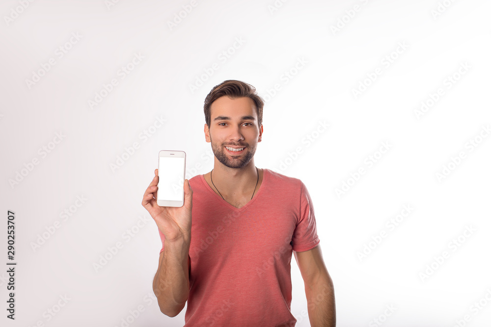 Portrait of a handsome smiling casual dressed man holding in hand modern cellphone with blank display with mock up copy space background for promotional content, standing isolated in studio Portrait of a handsome smiling casual dressed man holding in hand modern cellphone with blank display with mock up copy space background for promotional content, standing isolated in studio
