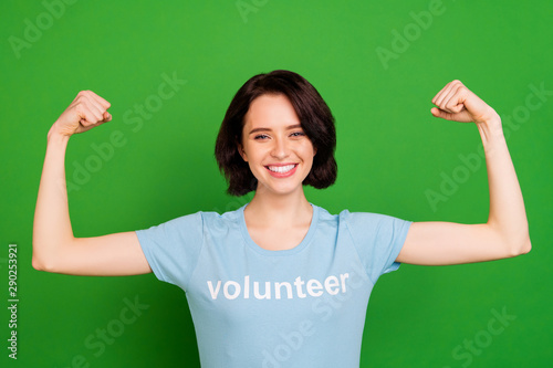 Close-up portrait of her she nice attractive cheerful cheery confident girl wearing blue t-shirt demonstrating arms muscles sport devotion isolated over bright vivid shine vibrant green background