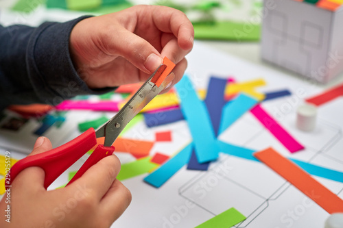 A childrens craft session in front of a teacher cutting up colourful paper with scissors