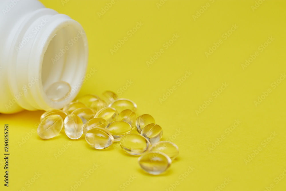 capsules from pharmaceutical medicine, pills and capsules and a bottle on a yellow background. Copy space for text. concept of medecine and vitamins in pills.