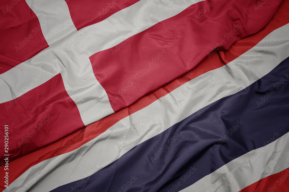waving colorful flag of thailand and national flag of denmark.