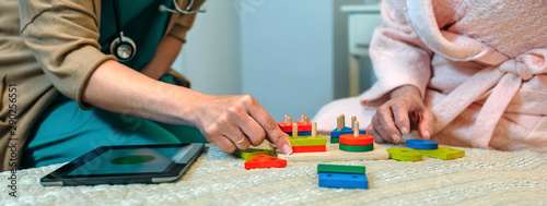 Female doctor showing geometric shape game to elderly female patient with dementia photo