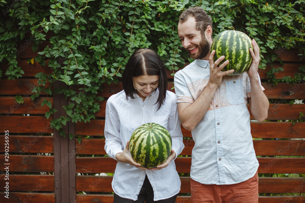 Fototapeta premium Portrait of a happy couple with a watermelon in their hands. Wooden background.