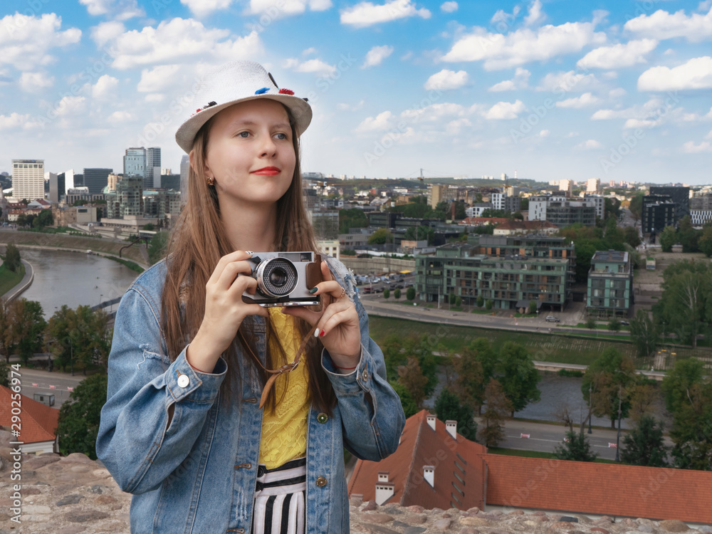 A beautiful teenager girl walks around the city and photographs everything with a vintage camera. Tourism. Vacation Vilnius.