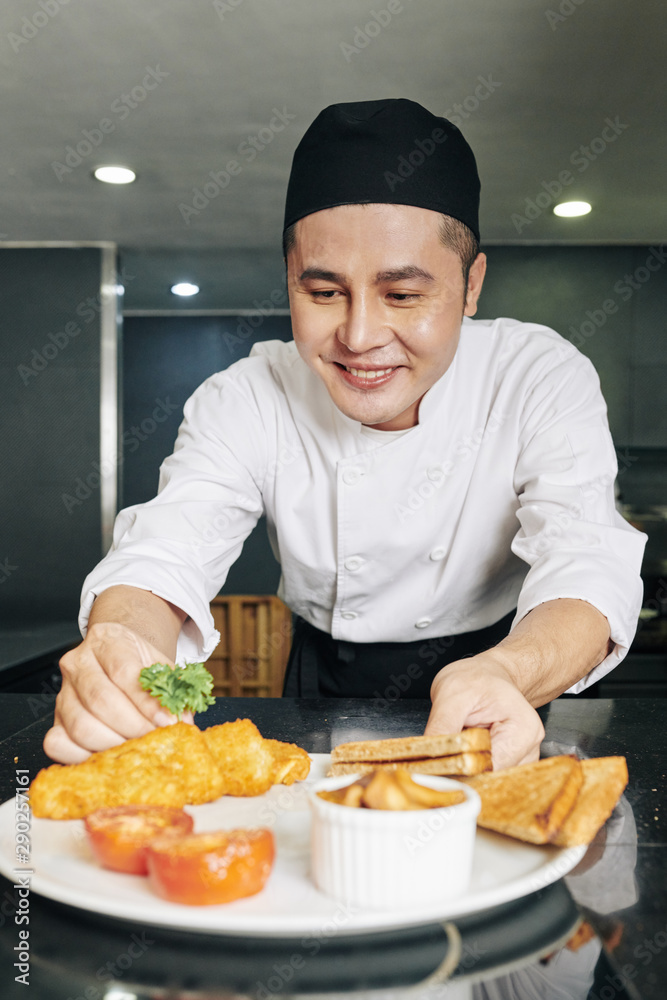 Asian young cook smiling and decorating his dish before serving at the restaurant Asian young cook smiling and decorating his dish before serving at the restaurant