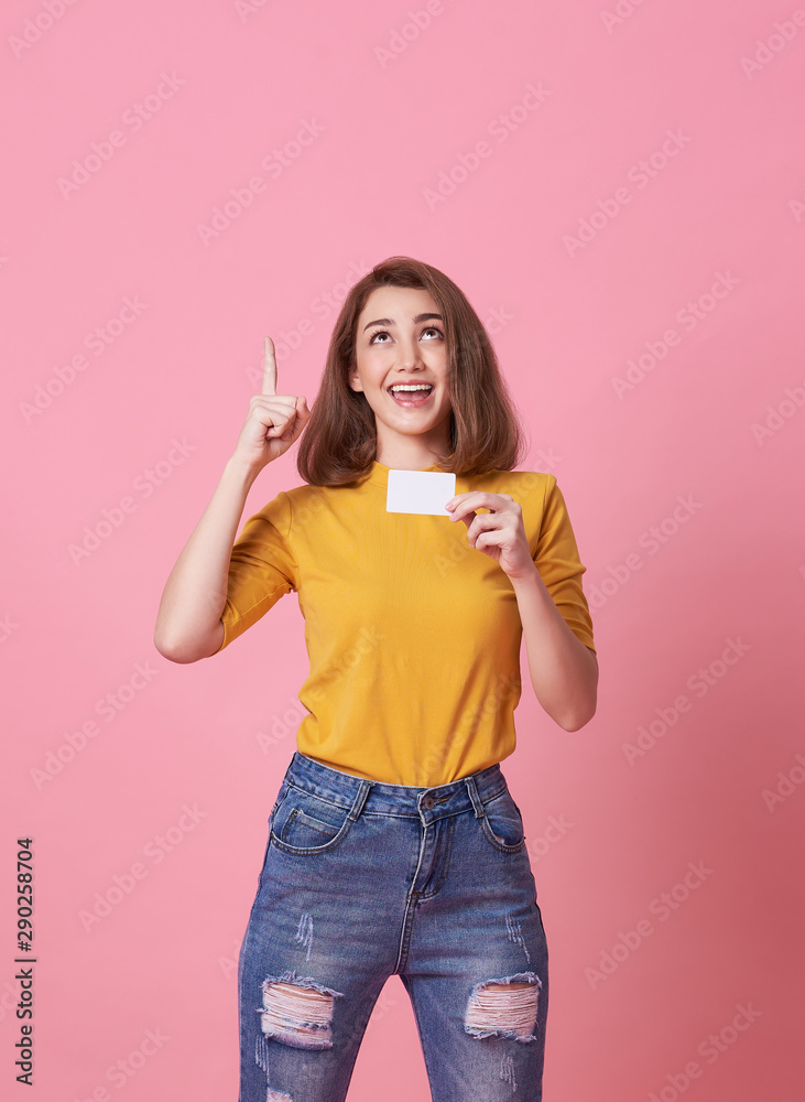 Portrait of an excited young woman showing credit card and hand point at copy space isolated over pink background. Portrait of an excited young woman showing credit card and hand point at copy space isolated over pink background.