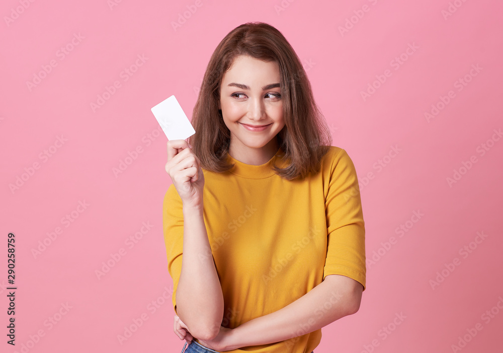 Portrait of a young woman showing credit card and looking isolated over pink background Portrait of a young woman showing credit card and looking isolated over pink background