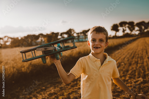 cute little boy playing outdoor with wooden airplane toy