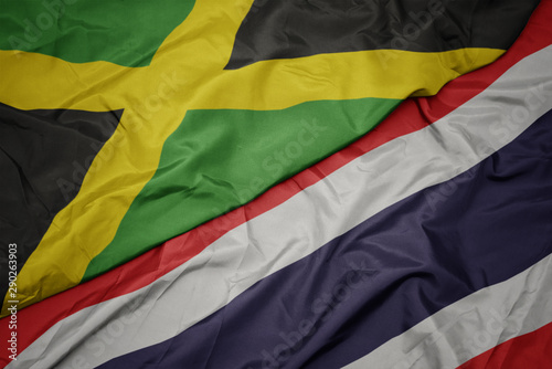 waving colorful flag of thailand and national flag of jamaica.