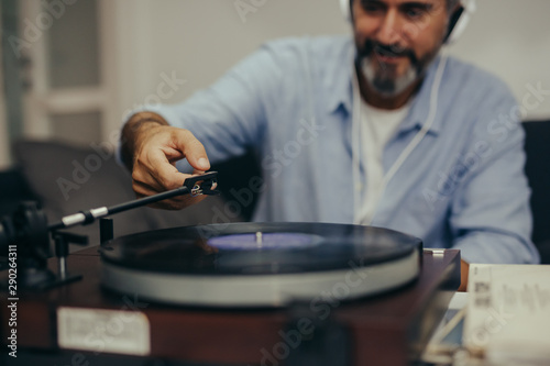 close up of middle aged man sitting sofa and listening music on record player in his home