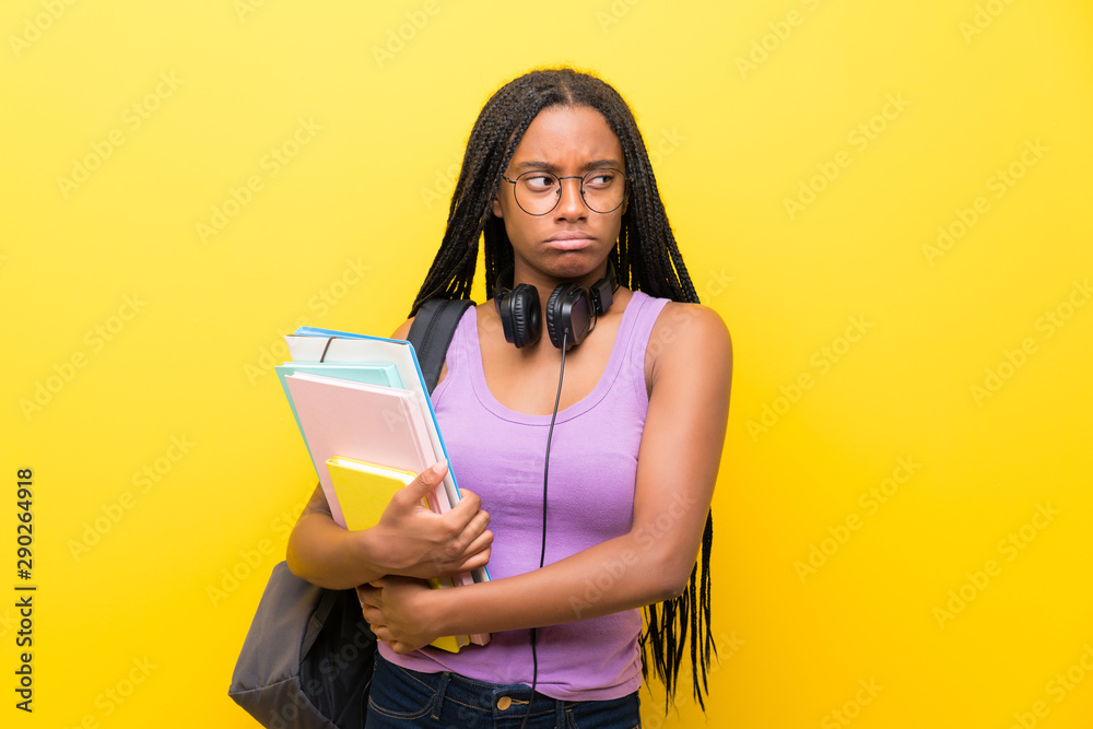 African American teenager student girl with long braided hair over isolated yellow wall thinking an idea African American teenager student girl with long braided hair over isolated yellow wall thinking an idea