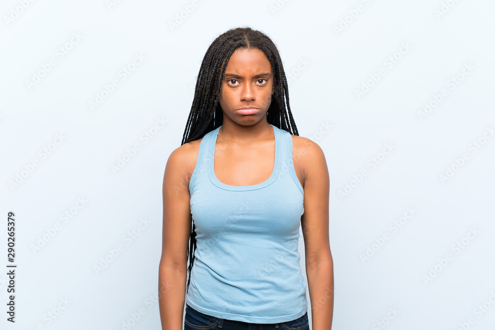 African American teenager girl with long braided hair over isolated blue background sad African American teenager girl with long braided hair over isolated blue background sad