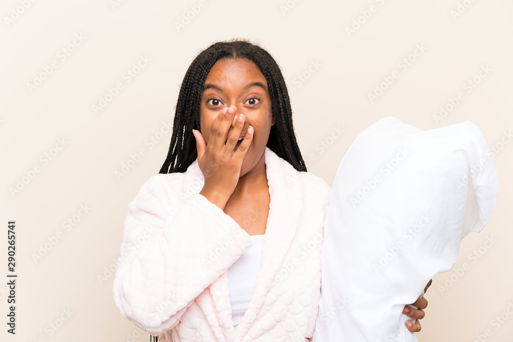 African American teenager girl with long braided hair in pajamas over isolated background with surprise facial expression African American teenager girl with long braided hair in pajamas over isolated background with surprise facial expression