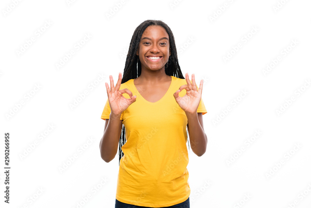 African American teenager girl with long braided hair over isolated white background showing an ok sign with fingers African American teenager girl with long braided hair over isolated white background showing an ok sign with fingers